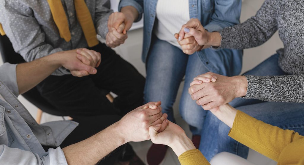 Group of people holding hands together.